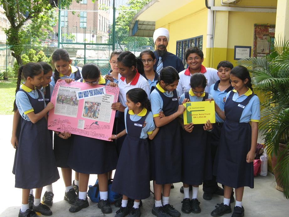 Students standing with School Director, Mr Sukdev Singh, holding up the Cheque and Poster